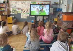 Dzieci oglądają fil edukacyjny o produktach ekologicznych.