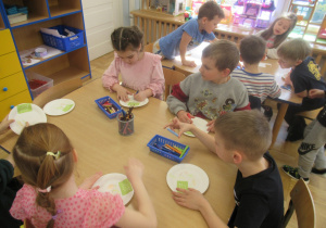 Dzieci przy stolikach wykonują prace plastyczne "Talerz zdrowia".