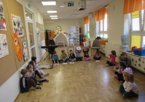 Dzieci siedzą na podłodze podczas rytmiki.