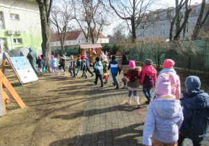 Dzieci maszeruja w parach po ogródku przedszkolnym.