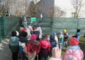 Dzieci stoją w parach, pani pokazuje dzieciom tabliczkę z napisem meta.