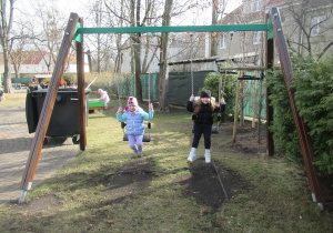 Dziewczynki huśtają się na huśtawkach.