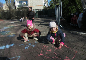 Dziewczynki rysują kredą.