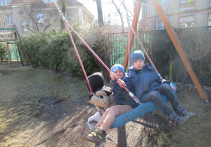 Dzieci bawią się na huśtawce - bocianim gnieździe na placu zabaw.