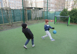 Chłopcy grają w piłke na boisku.