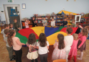 Dzieci stoją wokół chusty animacyjnej.