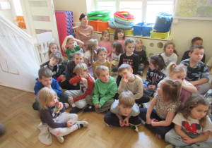 Dzieci siedzą na podłodze.