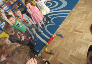 Dzieci stoją obok ułożonej z szarf litery c.