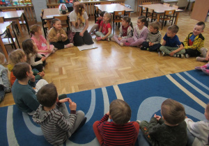 Dzieci siedzą w kole podczas zajęć Roar Dance.