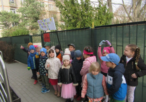 Dzieci stoją trzymając transparent z napisem Bielańskie Przedszkolaki Maszerują.