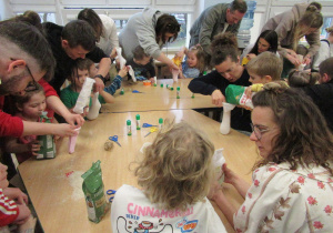 Dzieci z rodzicami przy stolikach podczas warsztatów.