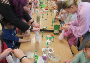 Dzieci i rodzice wykonują zajączki podczas warsztatów.