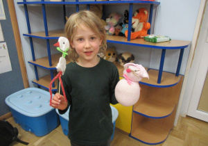 Chłopiec prezentuje bociana i zająca wykonane podczas warsztatów z rodzicami.