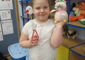 Dziewczynka prezentuje zająca i bociana wykonane podczas warsztatów wiosenno - wielkanocnych.