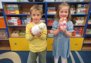 Dziewczynka i chłopiec prezentują zajączki wykonane podczas warsztatów z rodzicami.