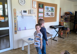 Dwóch chłopców stoi tyłem do siebie, by sprawdzić który z nich jest wyższy, a który niższy