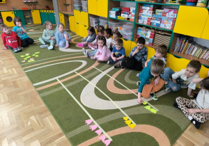 Chłopiec układa papierowe kwiaty na linii wyzaczonej taśmą malarką