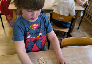 Chłopiec układa wzór z zapałek