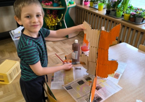 Chłopiec maluje lisa wykonanego z tektury i patyczków laryngologicznych