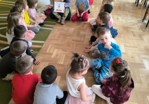 Dzieci słuchają pogadanki na temat baletu prowadzonej przez mamę jednego z chłopców