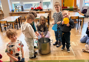 Dziewczynka miesza w garnku obrazki przedstawiające "składniki" marcowej pogody