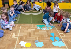 Chłopiec układa papierowe wiosenne kwiaty w konturze garnka wyklejonego taśmą malarską