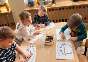 Chłopcy kolorują obrazki przedstawiające garnki