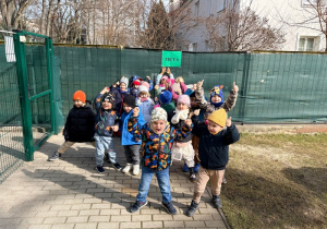 Dzieci stoją przed napisem "Meta" umieszczonym na płocie