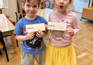 Dzieci trzymają kartki z napisem "burzowo"