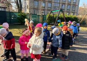 Dzieci spacerują po ogrodzie przedszkolnym z Marzannami