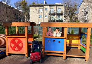 Dziewczynki bawią się na placu zabaw w drewnianym pociągu