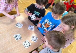 Dzieci oglądają naklejki zawierające różne liczby kropek (oczek)