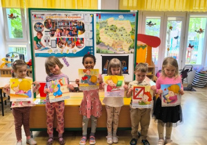 Dzieci trzymają ilustracje przedstawiające zasady obowiązujące w bibliotece