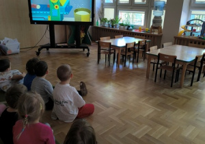 Dzieci oglądają film edukacyjny prezentujący jak powstaje papier