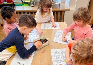 Dzieci kolorują obrazki przedstawiające kontenery na odpady