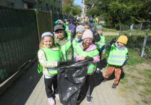 Dzieci pozują do zdjęcia z workiem na śmieci.