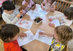 Dzieci kolorują obrazek przedstawiający rakietę kosmiczną