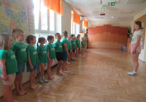 Dzieci stoja w szeregu podczas zajęć z elementami taekwondo.