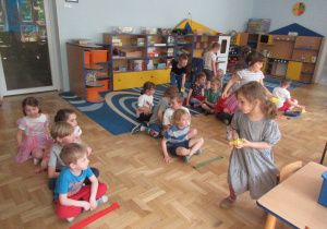 Dzieci siedzą w czterech rzędach i wykonują zadania.