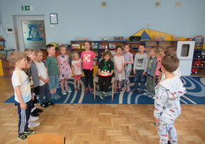 Chłopiec obchodzi urodziny, siedzi na krześle, pozostałe dzieci stoją w półkolu.