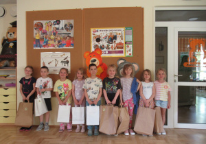 Dzieci pozują do zdjęcia z upominkami za udział w konkursie fotograficznym "Cyfry z natury".