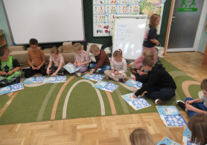 Dzieci siedzą na dywanie i pracują w książkach.