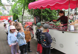 Pani nakłada dzieciom lody.