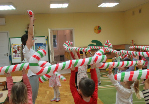 Przedszkolaki tańczą z balonami w kształcie cukrowych lasek.