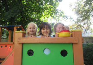 Dziewczynki stoją na sprzęcie na placu zabaw.