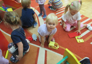 Przedszkolaki bawią się na dywanie.