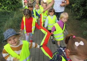 Przedszkolaki ubrane w odblaskowe kamizelki spacerują ulicami warszawskich Bielan.