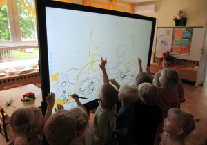 Dzieci rysują po tablicy multimedialnej.