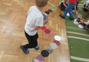 Dzieci układają na podłodze gąsienice z kółek.