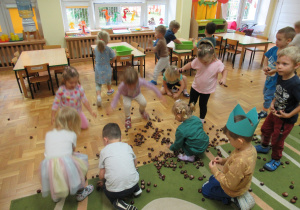 Dzieci zbierają rozrzucone w sali kasztany.